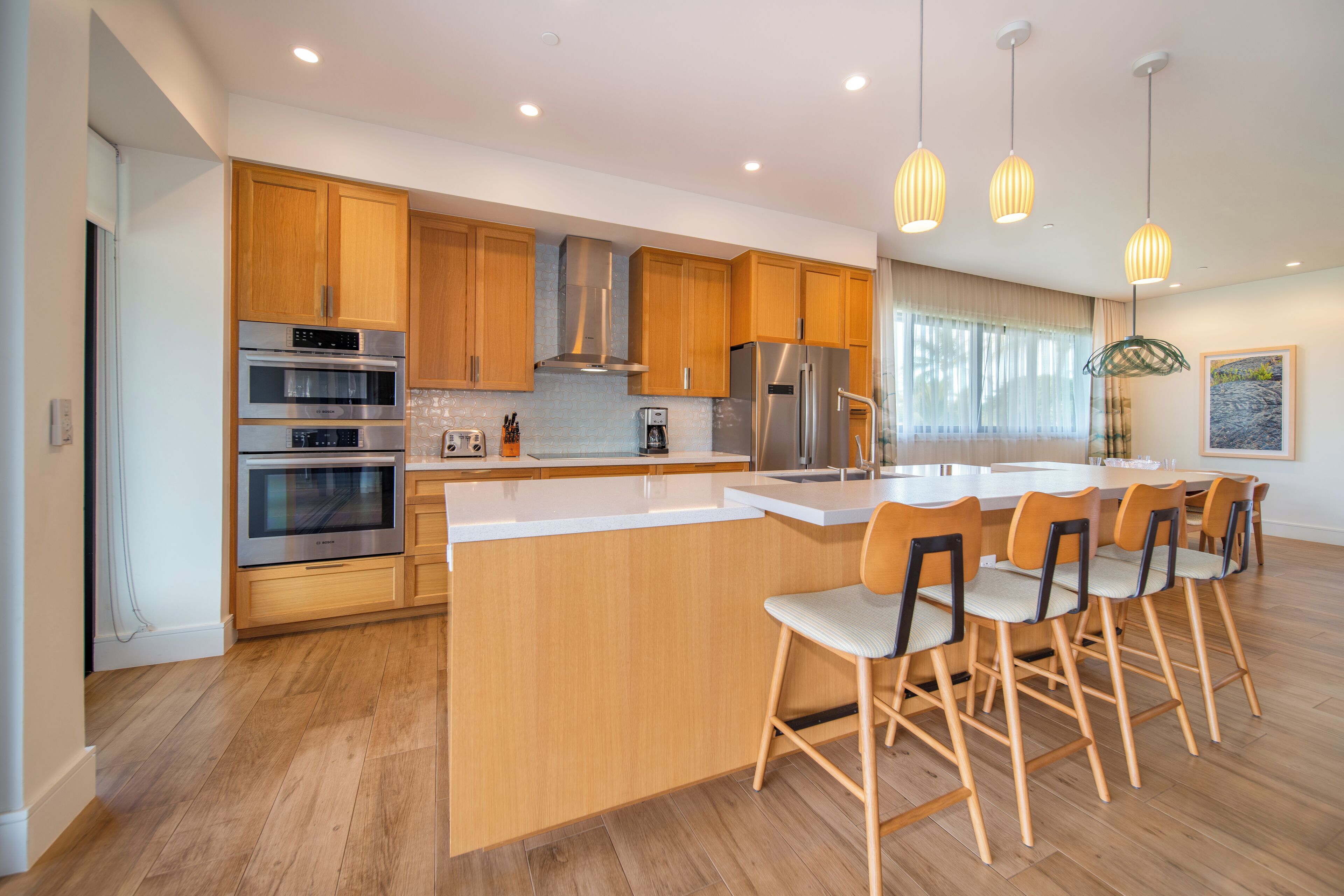 Una cocina moderna con armarios de madera, electrodomésticos de acero inoxidable y una isla central con taburetes de bar.