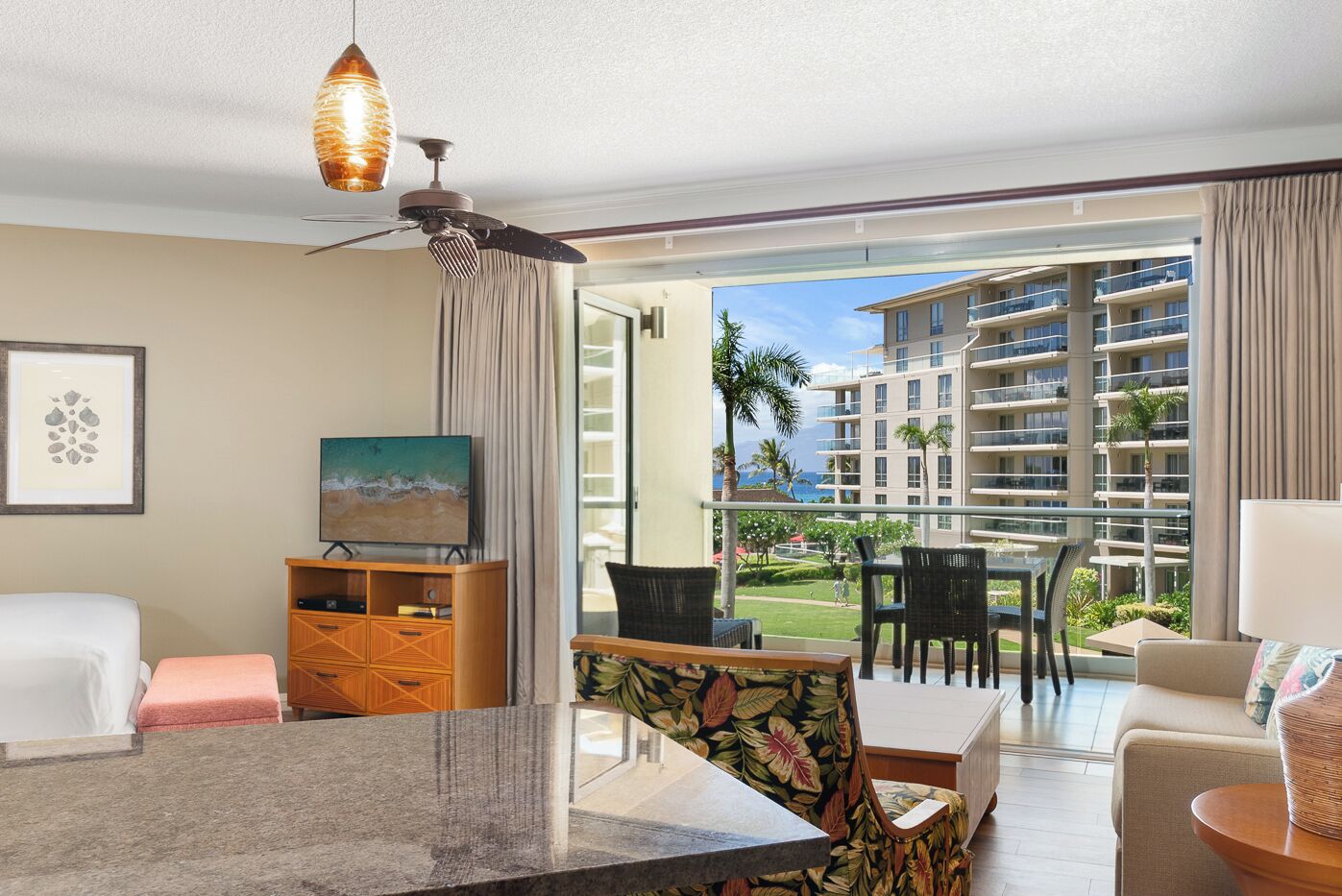 A hotel room with a balcony, a dining area, and a TV.