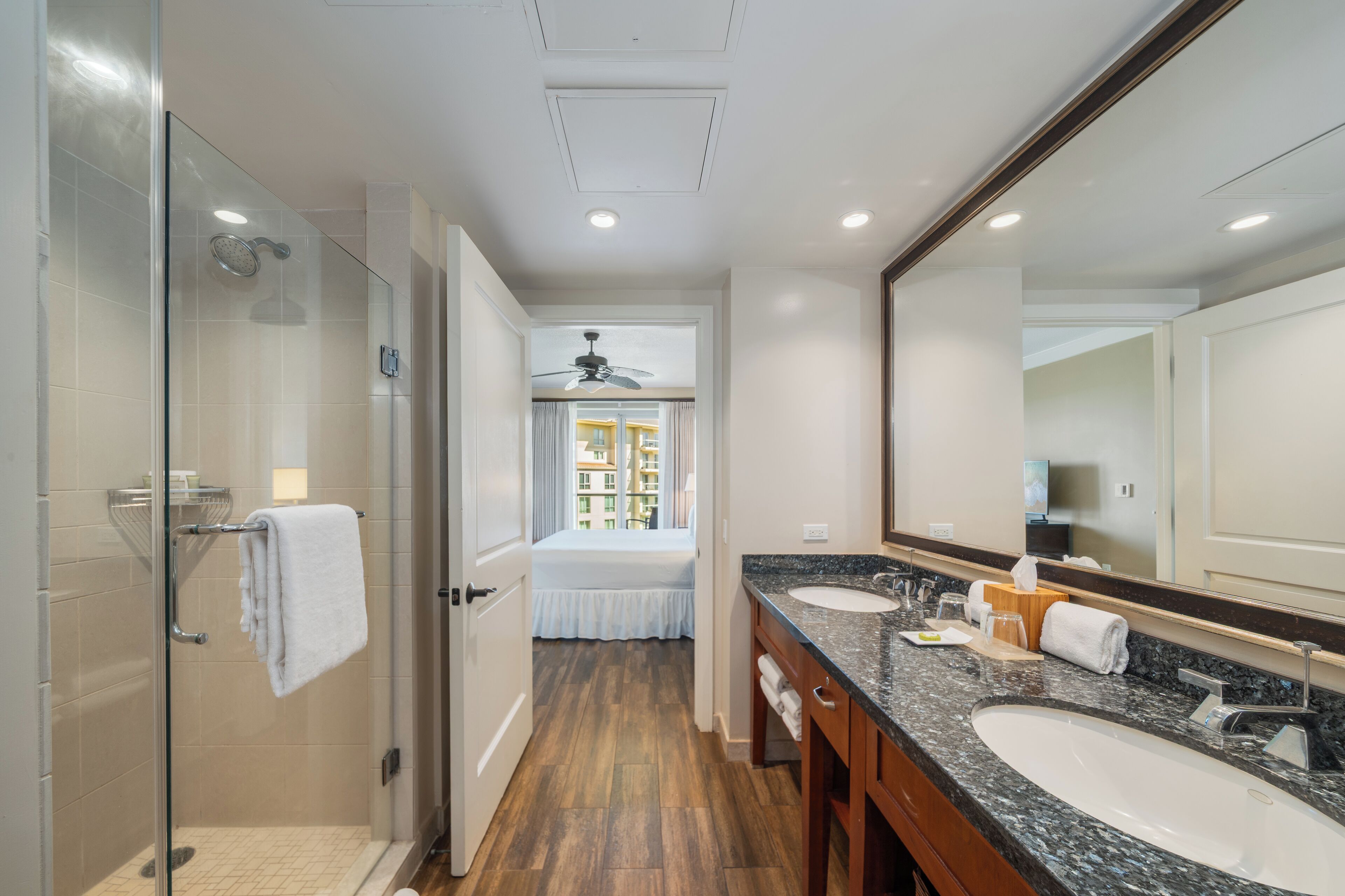 A modern bathroom with a glass-enclosed shower, a large mirror, and a vanity with two sinks.