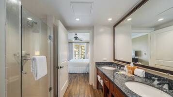 A modern bathroom with a glass-enclosed shower, a large mirror, and a vanity with two sinks.