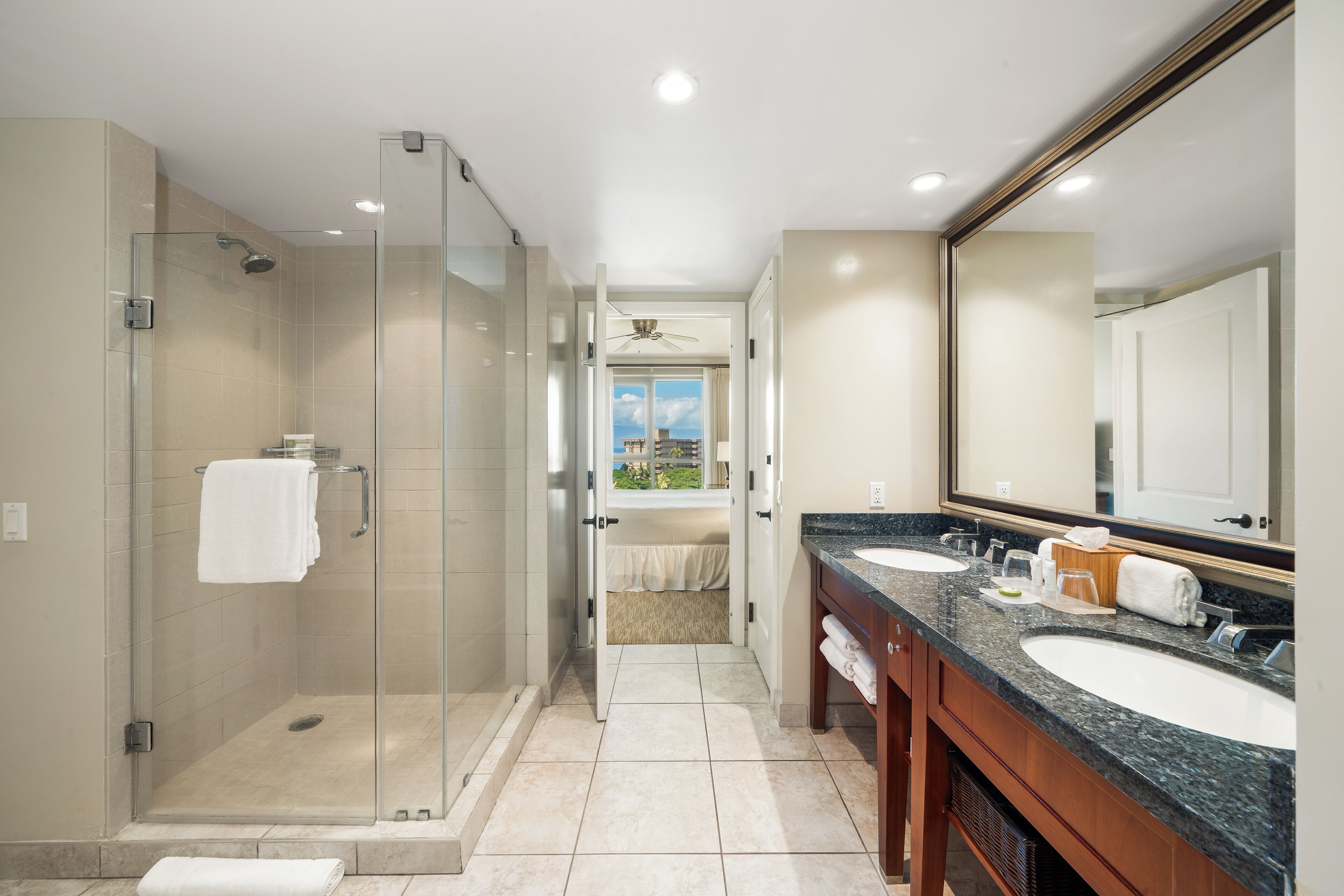 A modern bathroom with a glass-enclosed shower, two sinks, and a large mirror.