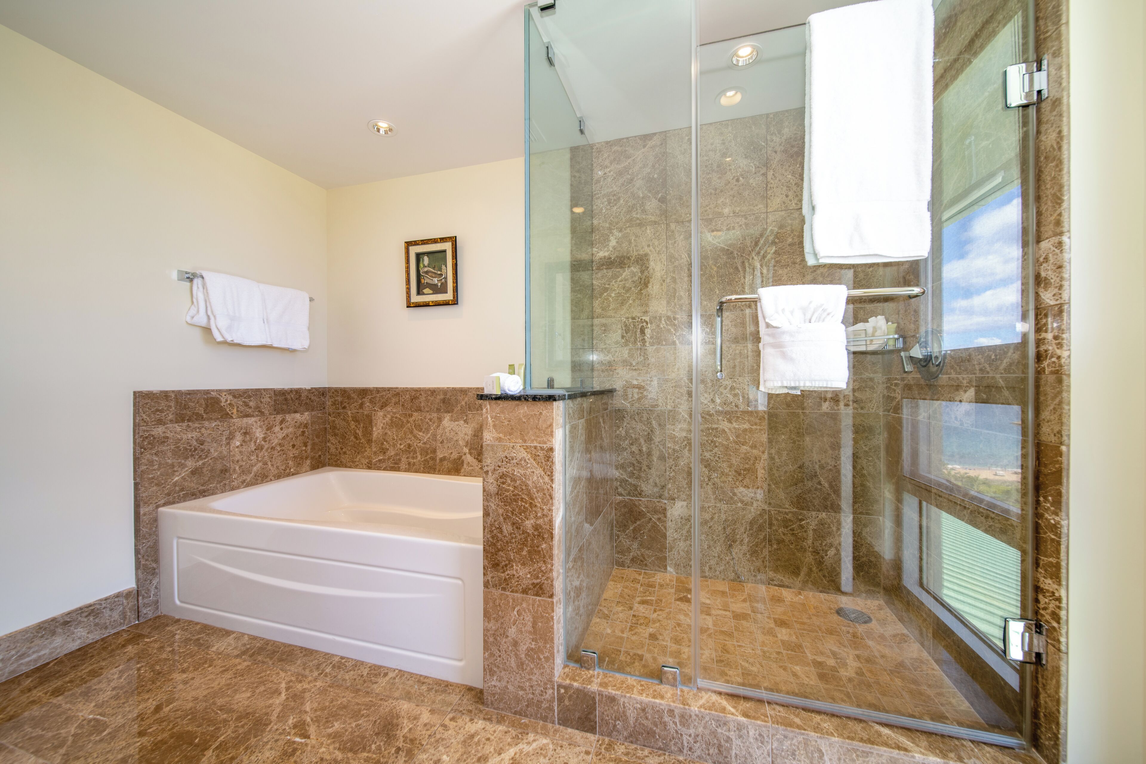 Un baño moderno con ducha envuelta en vidrio, una bañera independiente y suelo de mármol.