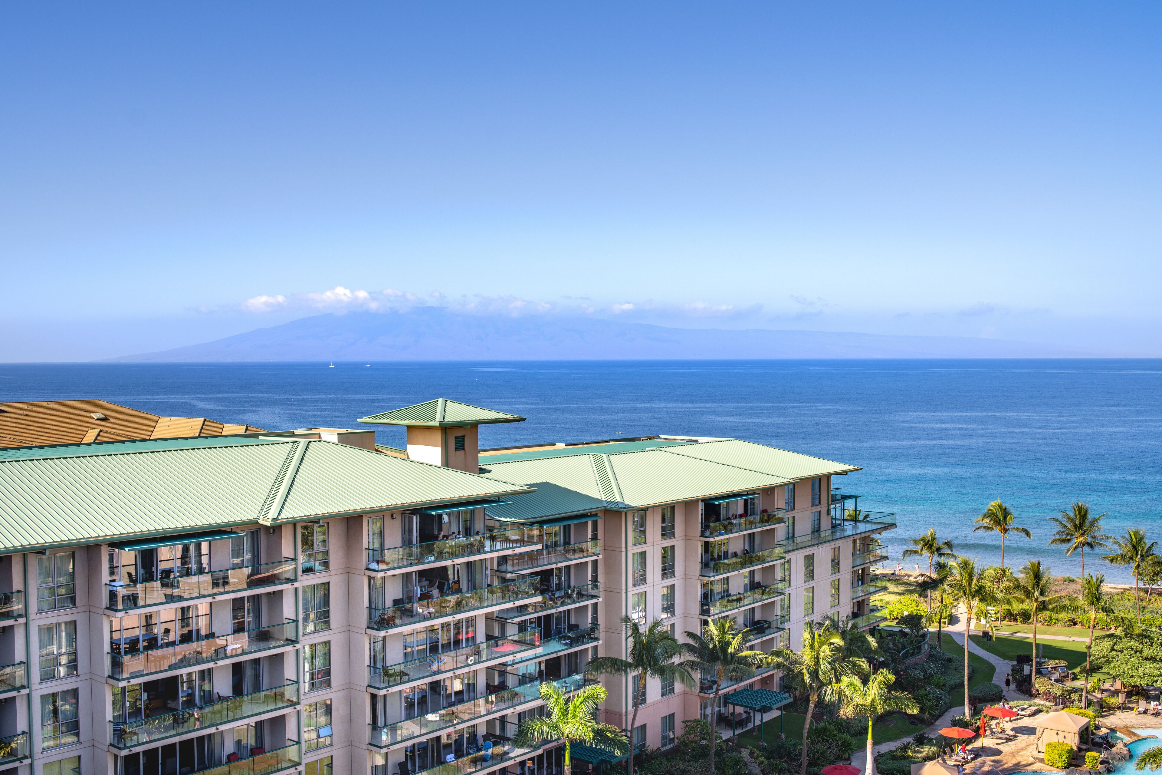 Ein mehrstöckiges Hotel mit Balkonen mit Blick auf einen Strand und den Ozean.