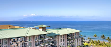A multi-story hotel with balconies overlooking a beach and ocean.