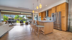 Une cuisine moderne avec des meubles en bois, un réfrigérateur en acier inoxydable et un coin bar avec des tabourets.