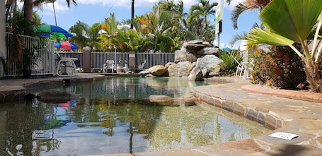 Una piscina al aire libre, sillones reclinables de piscina