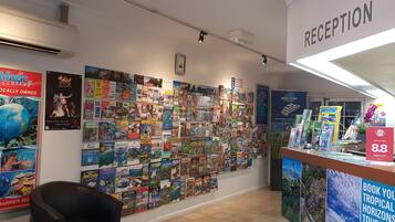 Un espace d’accueil avec un mur recouvert de brochures de voyage et un comptoir sur lequel est affiché un panneau indiquant un tarif de 88 dollars la nuit.