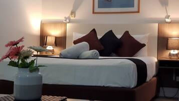 A neatly made bed with a white and brown headboard, two bedside lamps, and a vase with flowers on a bedside table.