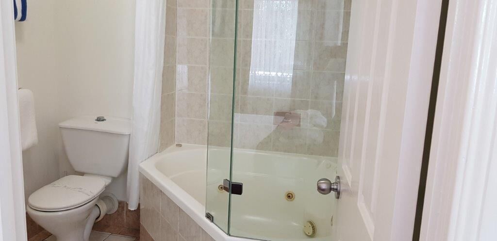 A bathroom with a toilet, a glass-enclosed shower, and a bathtub.