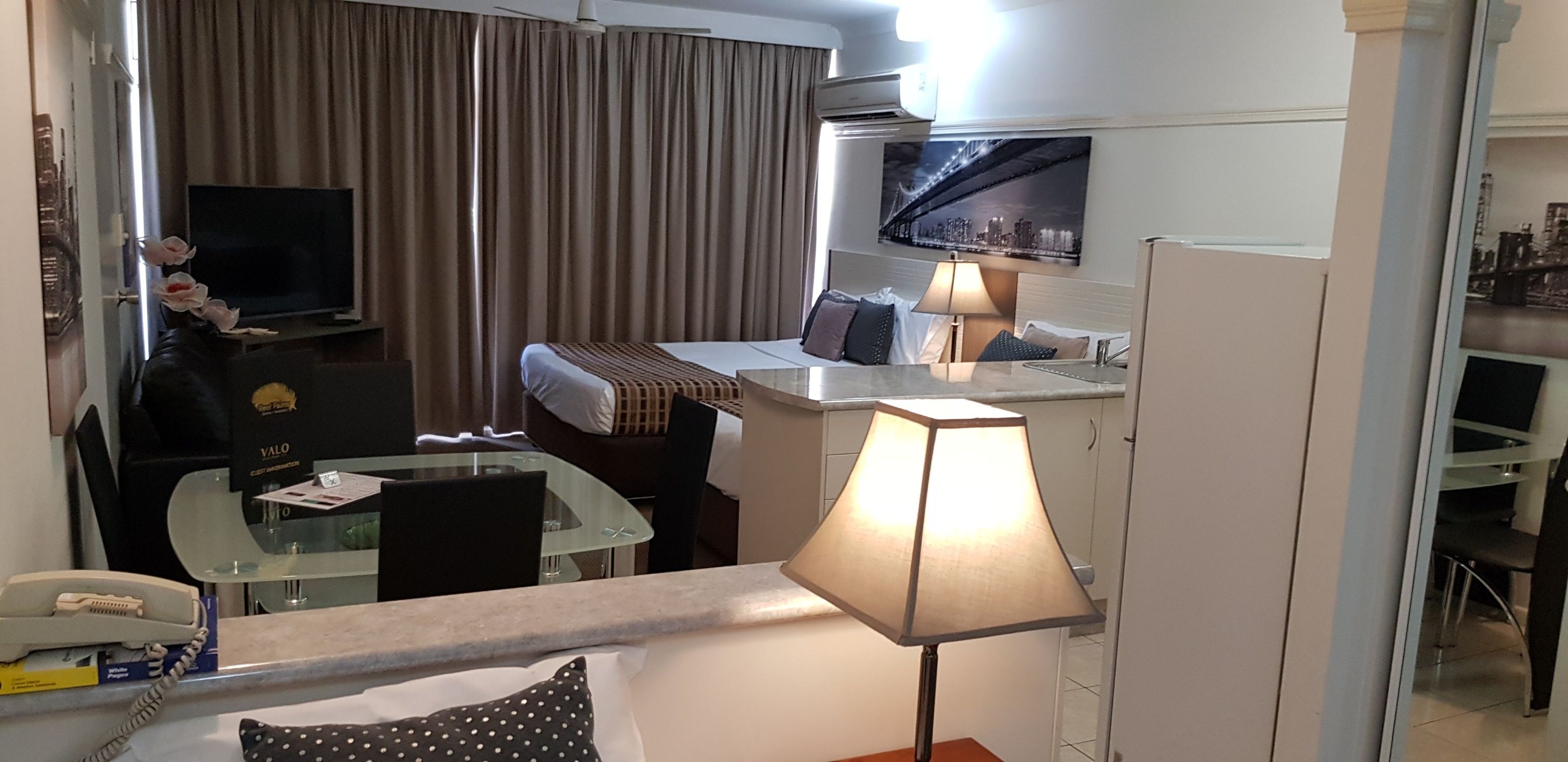 Une chambre d’hôtel équipée d’un lit, d’un bureau, d’une chaise, d’une lampe, d’une télévision et d’une fenêtre avec des rideaux.