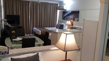 Une chambre d’hôtel équipée d’un lit, d’un bureau, d’une chaise, d’une lampe, d’une télévision et d’une fenêtre avec des rideaux.
