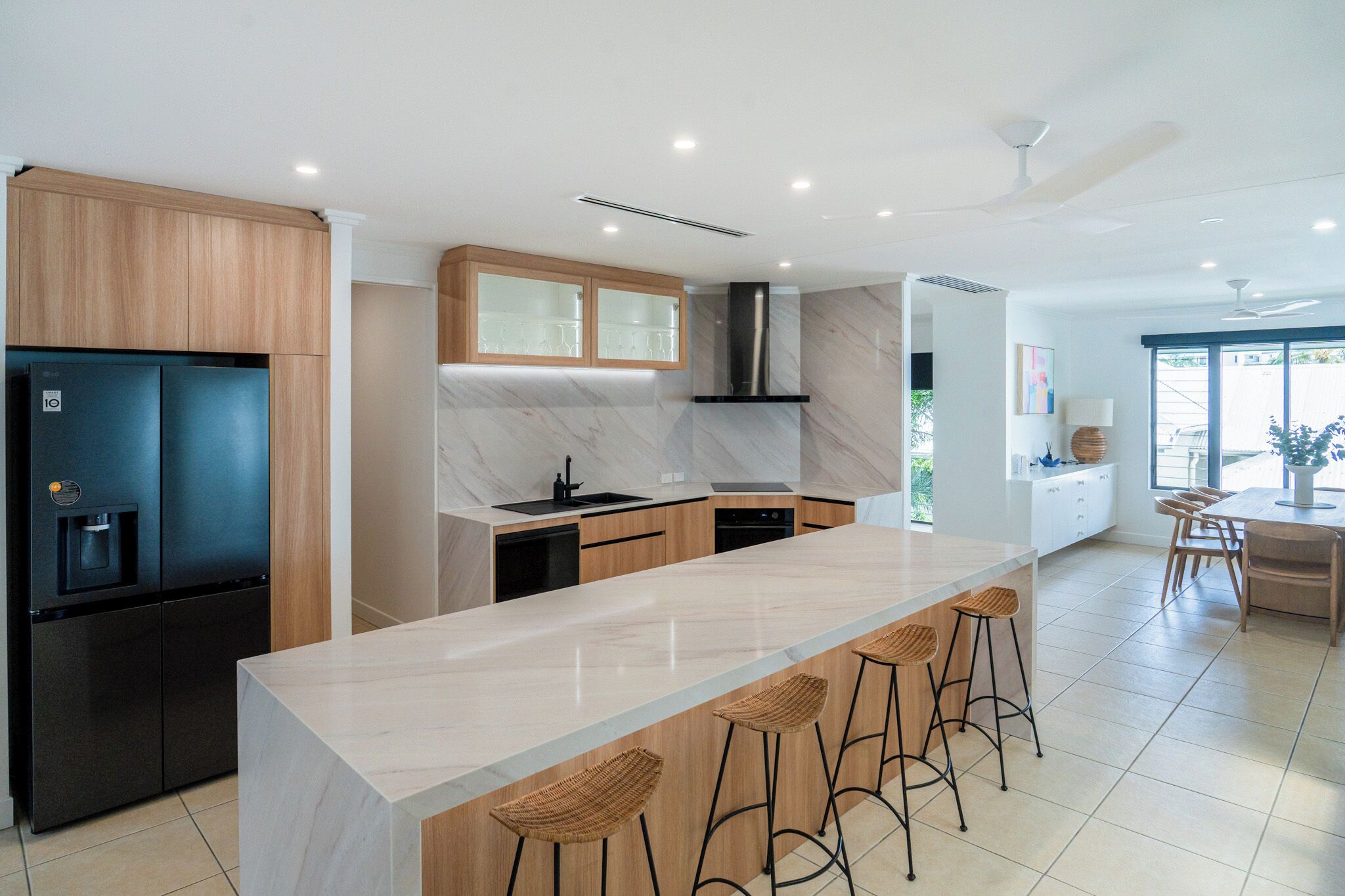 A modern kitchen with a central island, built-in appliances, and a large window providing natural light.
