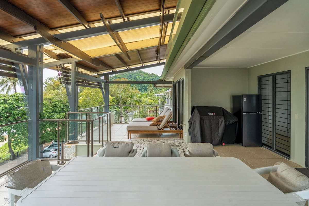 Ein Balkon mit überdachter Sitzgelegenheit, Grill und Kühlschrank.