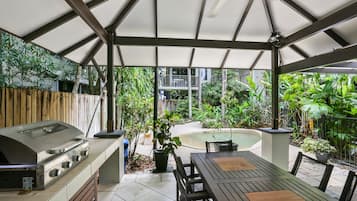 Un patio exterior con una parrilla, una mesa de comedor y sillas.