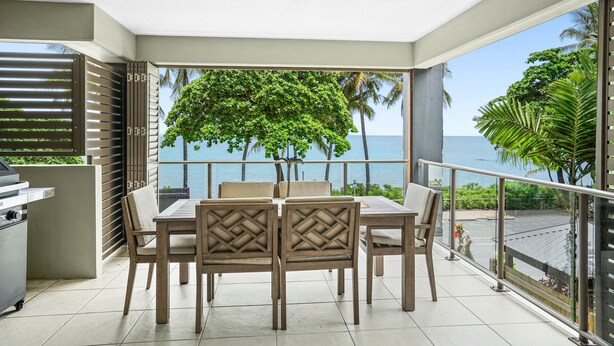 Un balcon avec une table et des chaises pour prendre les repas, un barbecue et une vue sur la mer.