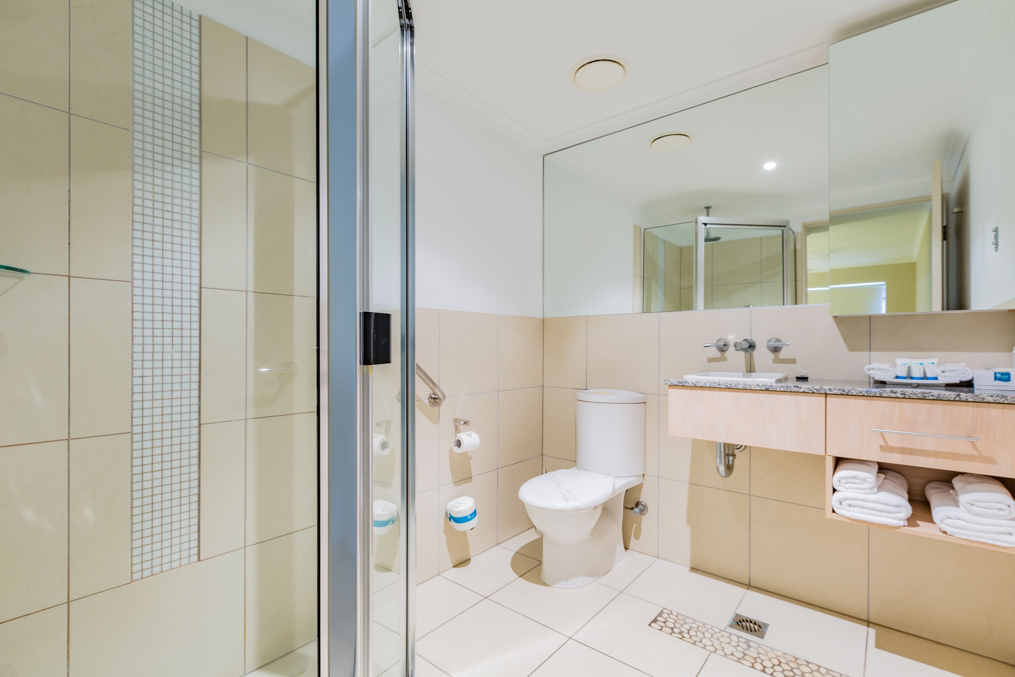 Ein modernes Badezimmer mit Duschkabine aus Glas, Toilette und Waschtisch mit Spiegel.