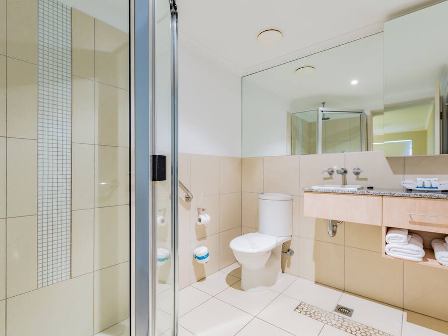 Ein modernes Badezimmer mit Duschkabine aus Glas, Toilette und Waschtisch mit Spiegel.
