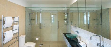 A modern bathroom with a glass-enclosed shower, a toilet, and two glass sinks with a large mirror.