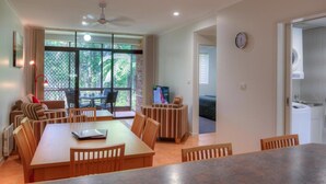 Amplia sala de estar con mesa de comedor, sillas y televisor. Balcón con vista a zonas verdes.