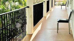 A covered outdoor area with a concrete floor, a black metal railing, and a bench. - Coconut Grove Holiday Apartments (Coconut Grove)