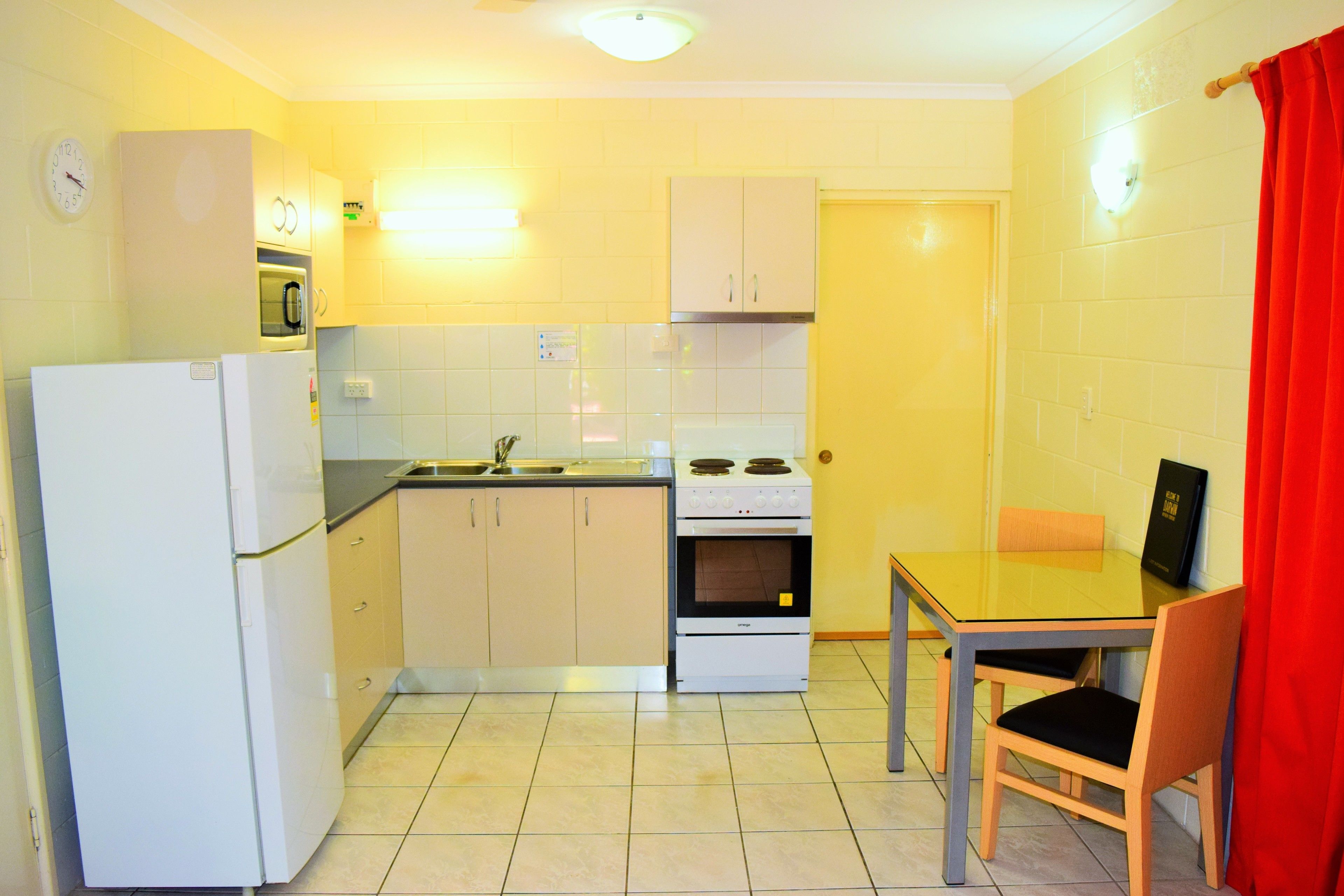 Cocina compacta equipada con refrigerador, horno y microondas.