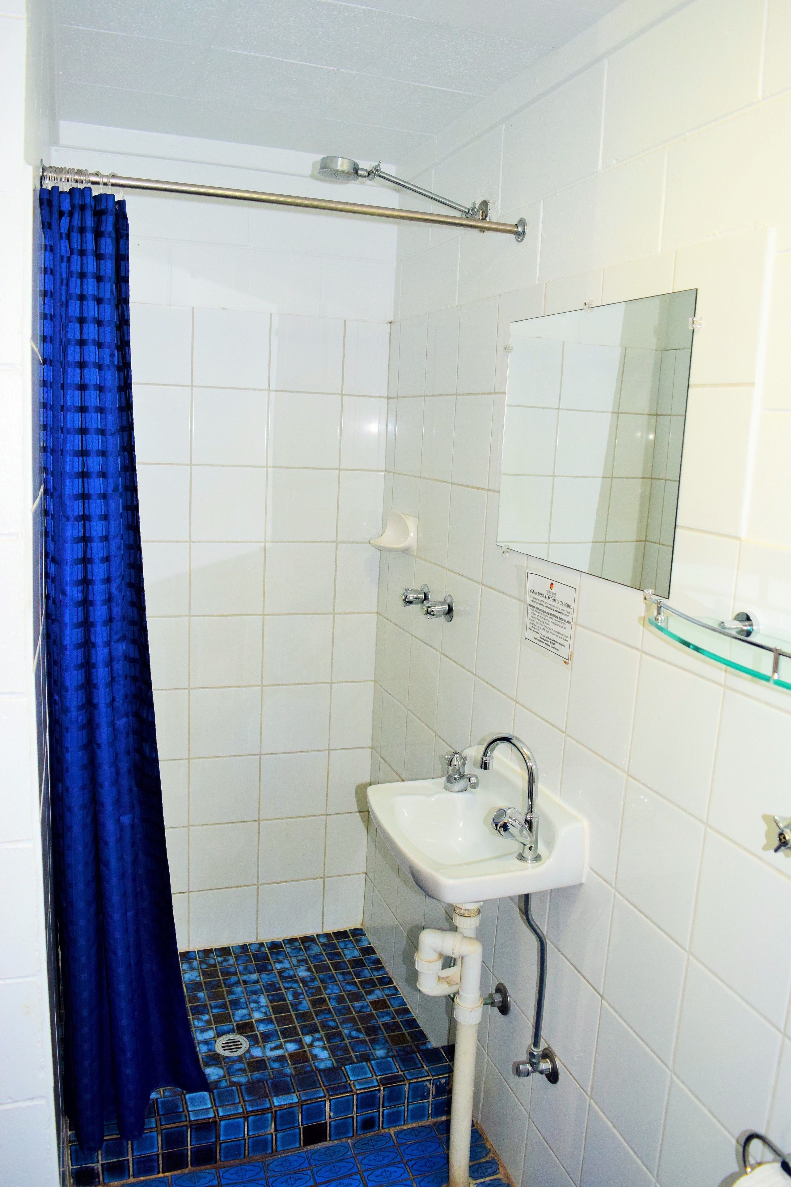 A bathroom with a shower, a sink, and a mirror.