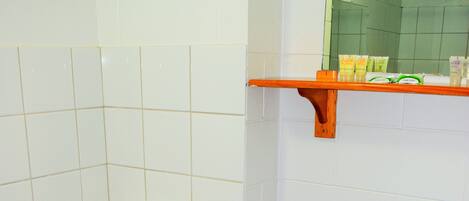 Un baño con inodoro, suelo de patrón azul, azulejos blancos y un estante con artículos de aseo.