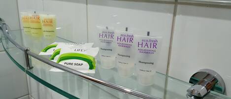 Un baño con un estante de vidrio que exhibe diversos productos para el cabello.