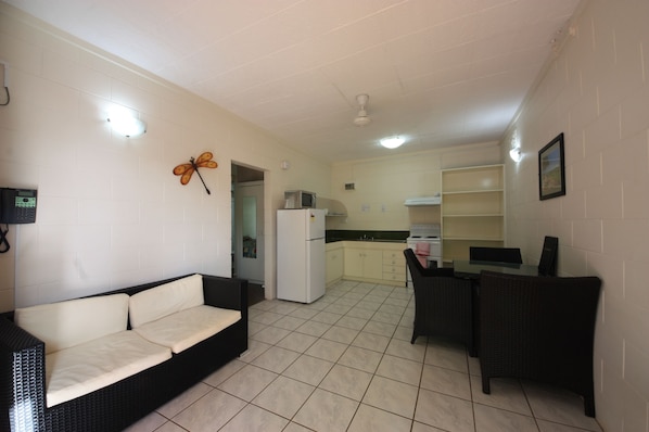 A compact living space with a sofa, dining table, chairs, a kitchen area, and a ceiling fan.