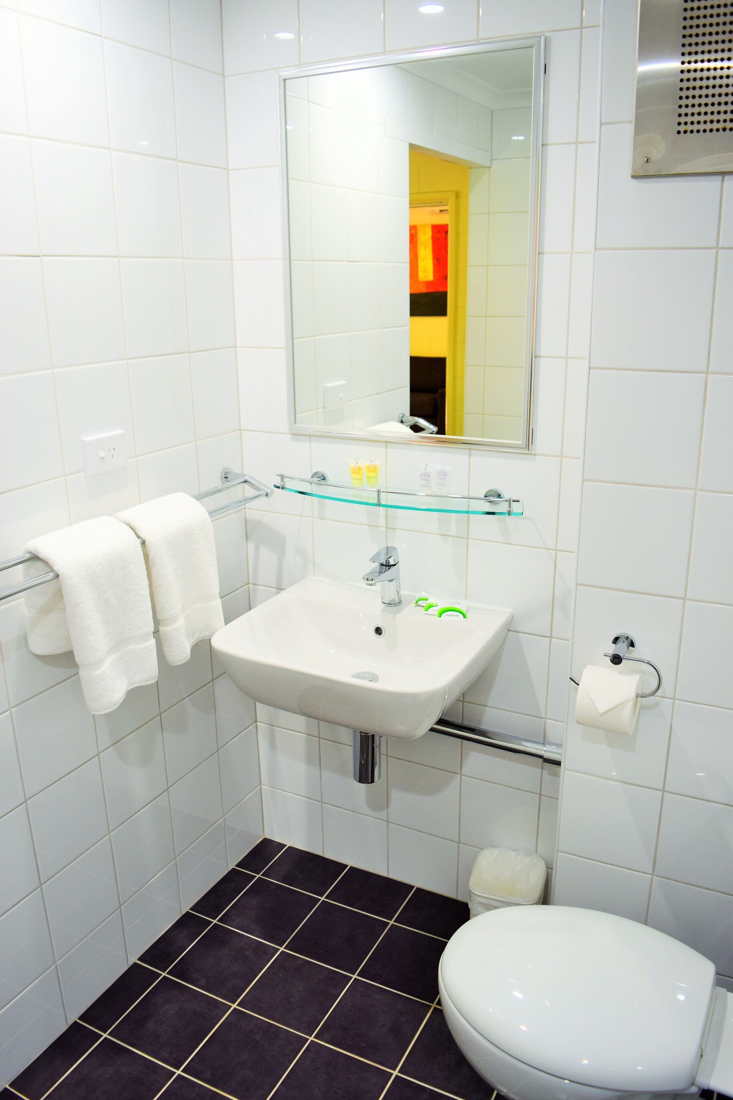 Une salle de bain avec un lavabo blanc, un miroir et des toilettes.