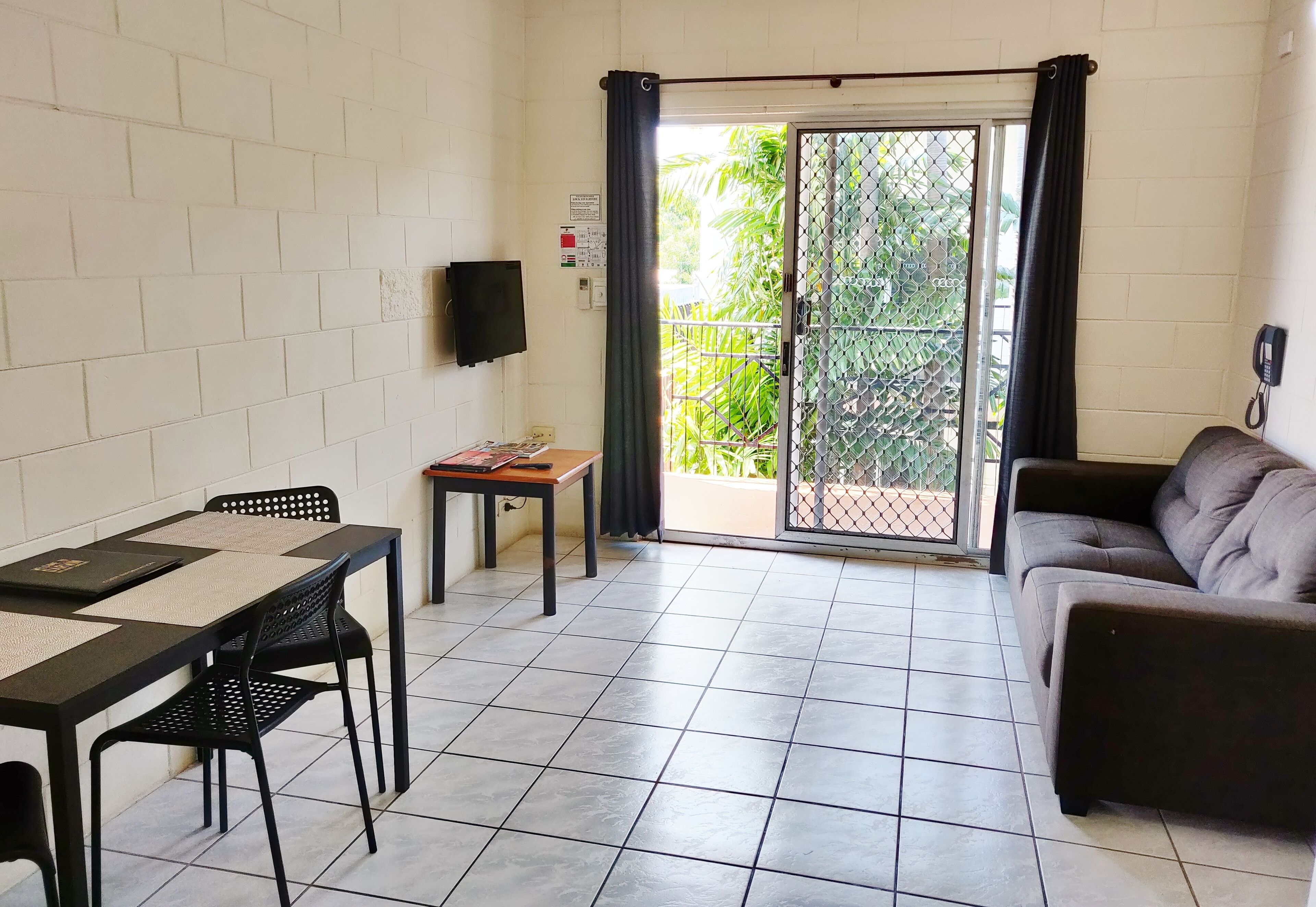 Una habitación con una mesa de comedor, sillas, un sofá y un ventanal corredero que da a un balcón.