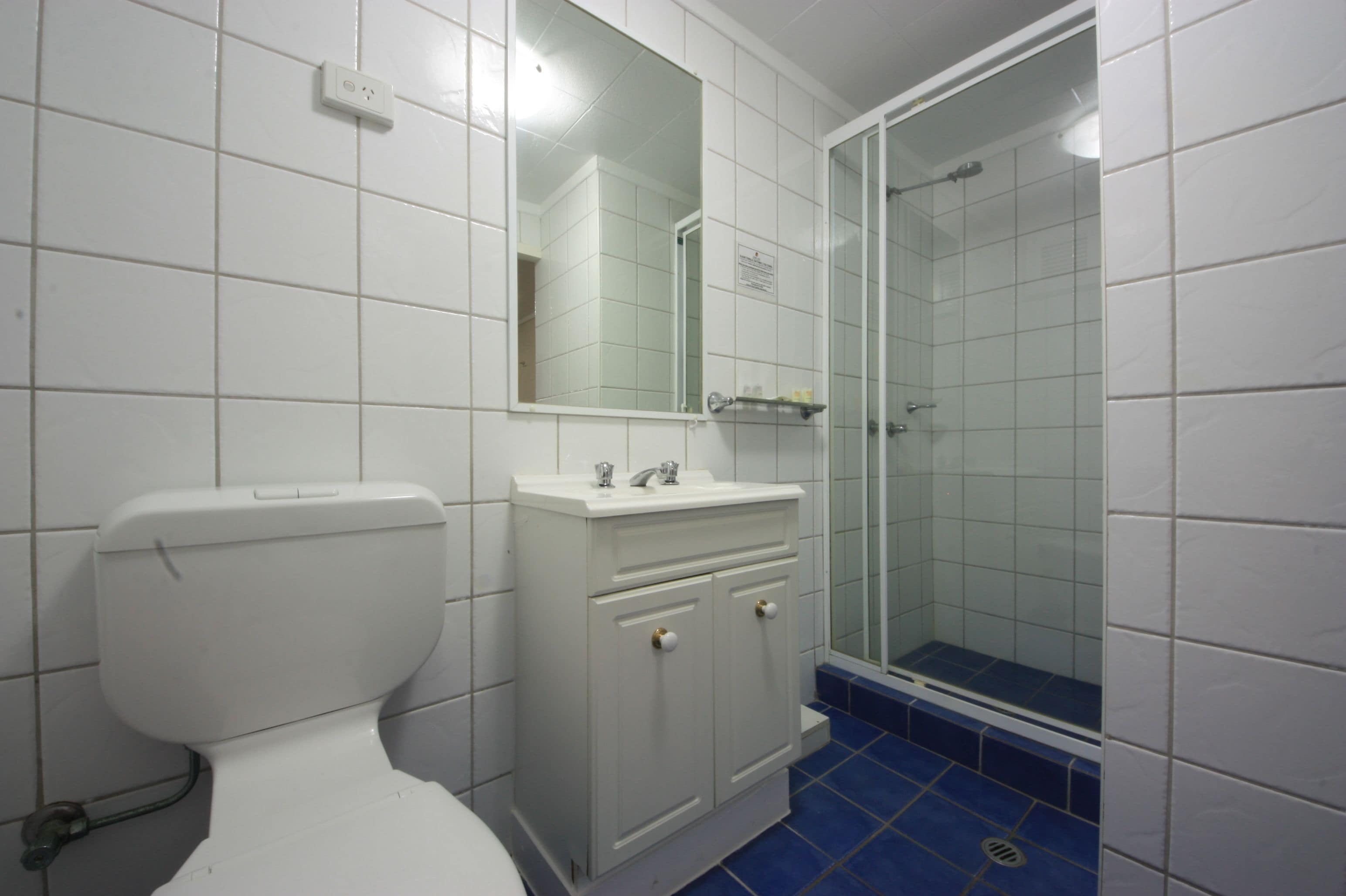 Une salle de bain comprenant des toilettes, un lavabo avec un miroir et une douche à parois en verre.