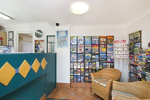 A reception area with a blue counter, a clock, and a wall filled with travel magazines.