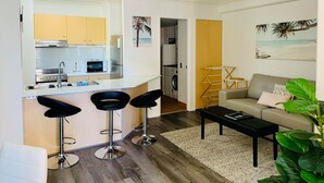 A compact living space with a kitchenette, a dining area with bar stools, a sofa, and a coffee table. - Aruba Surf Resort (Broadbeach)