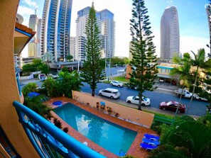A pool area with a view of tall buildings and a road with cars.