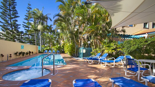 A pool area with lounge chairs and a hot tub. - Aruba Surf Resort (Broadbeach)