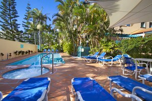 Zona de piscina con sillas de descanso y un jacuzzi.