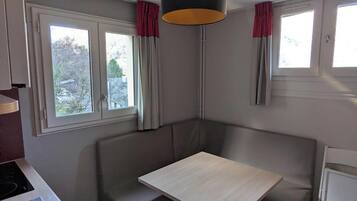 Une petite cuisine équipée comprenant un évier, une cuisinière, une petite table à manger et un banc.
