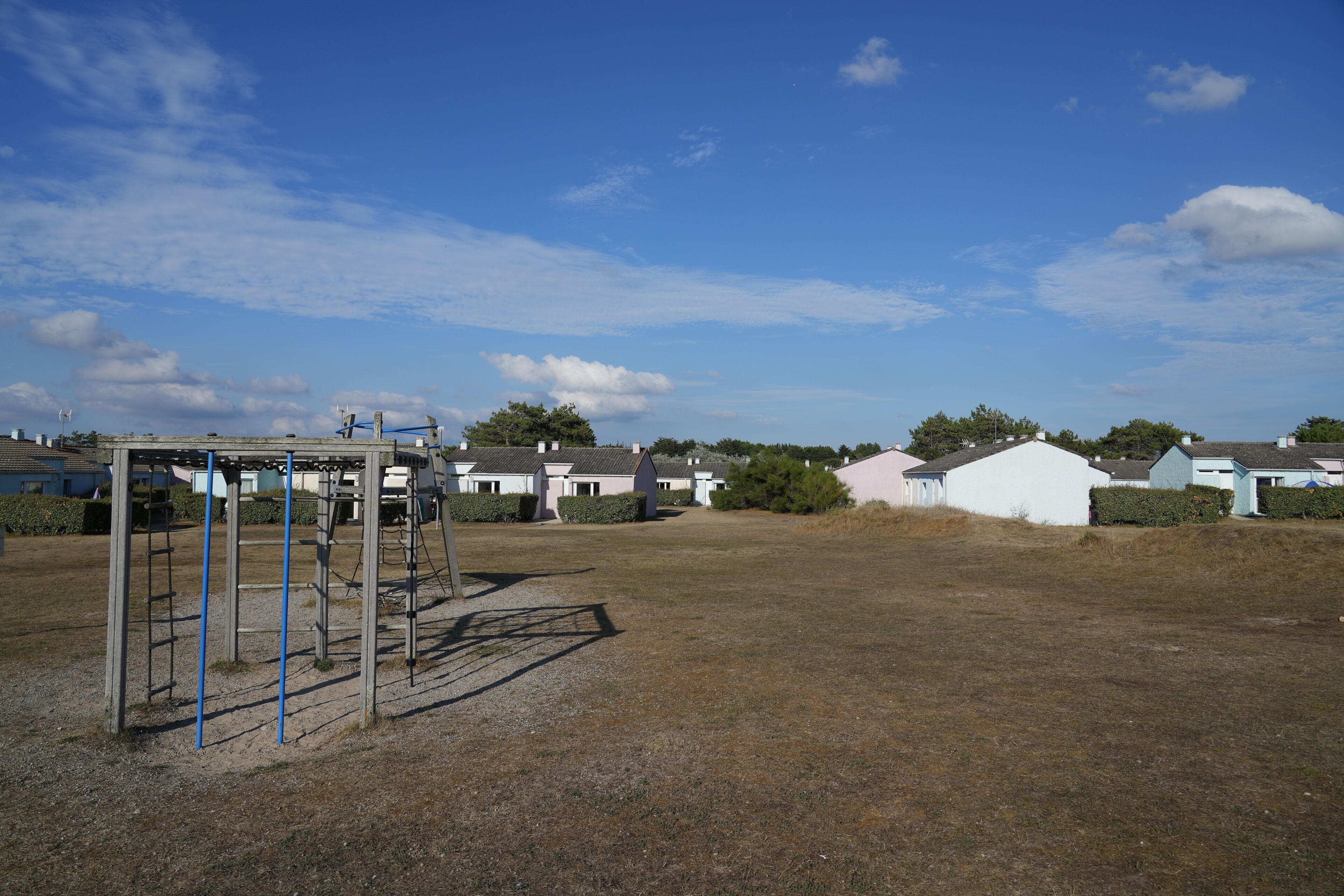 Zona residencial con casas, un parque infantil y cielo despejado.