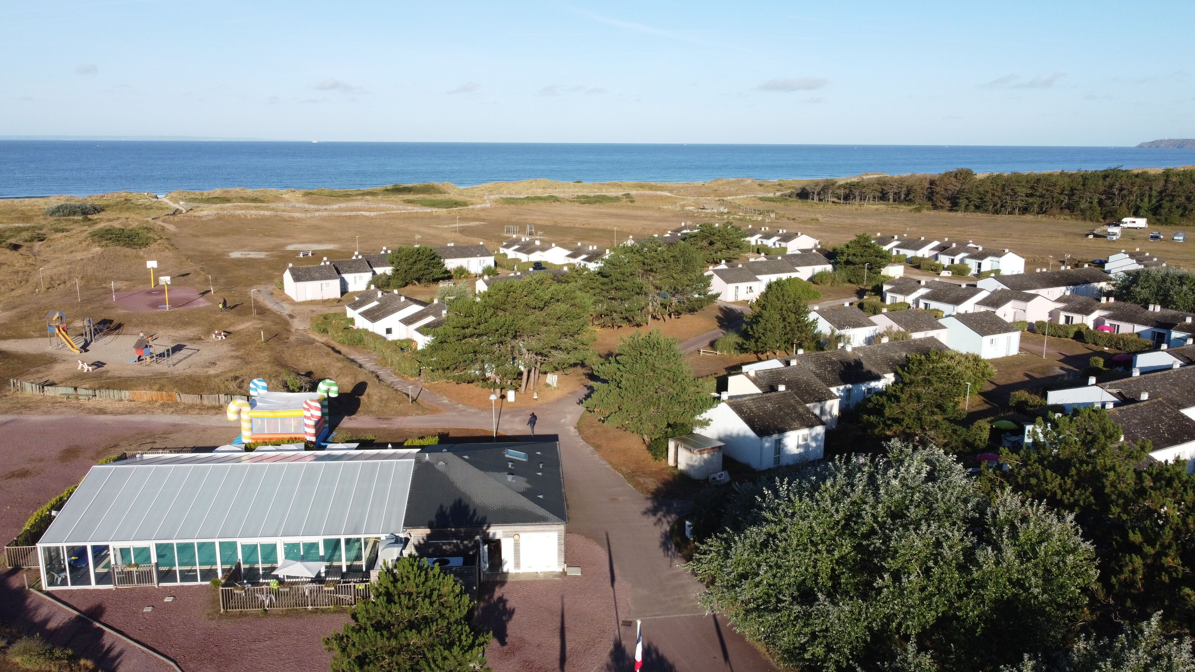 A coastal residential area with houses, a playground, and a building with a solar panel roof.