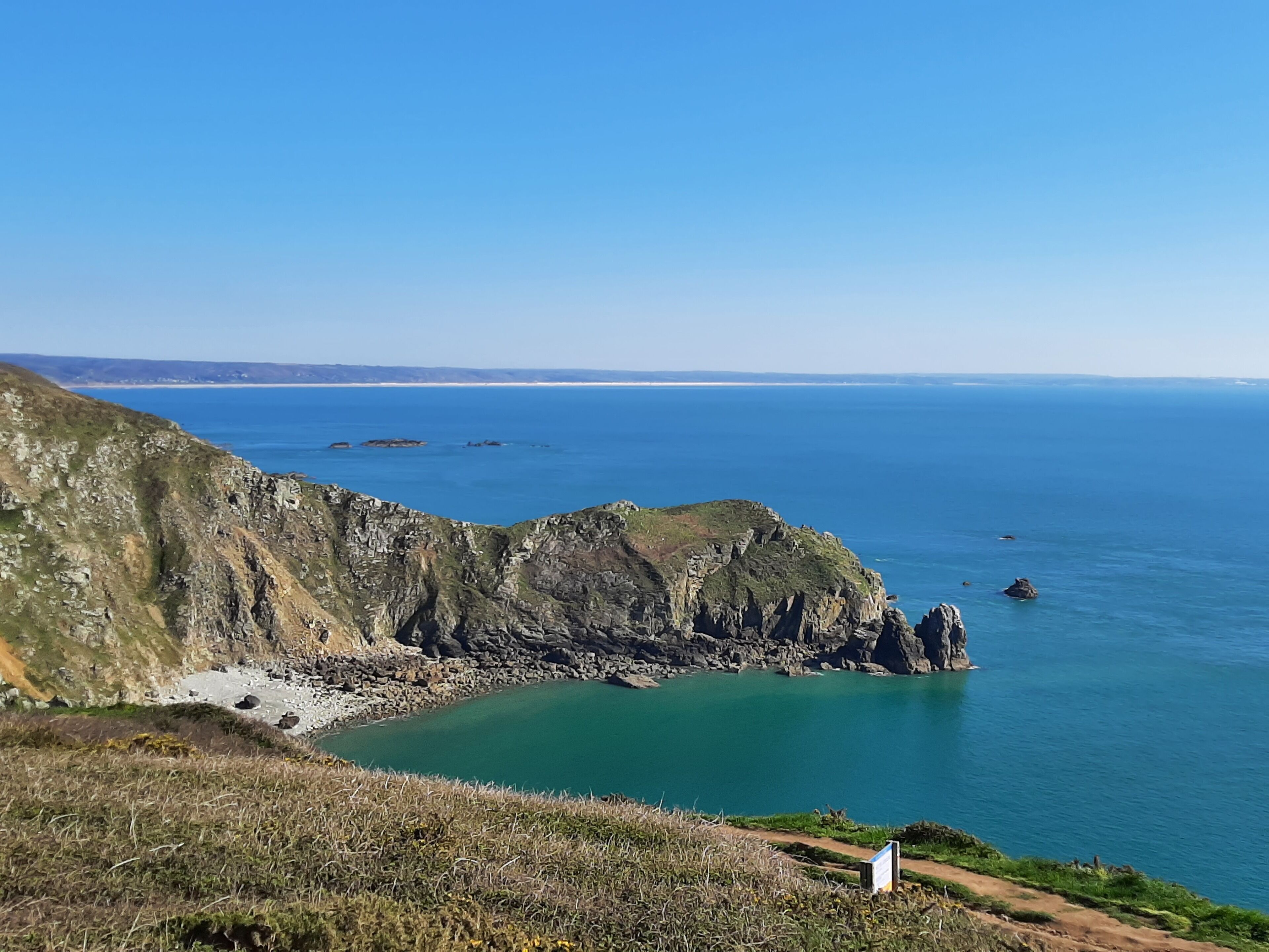 A coastal landscape with rocky cliffs and a clear blue sea.