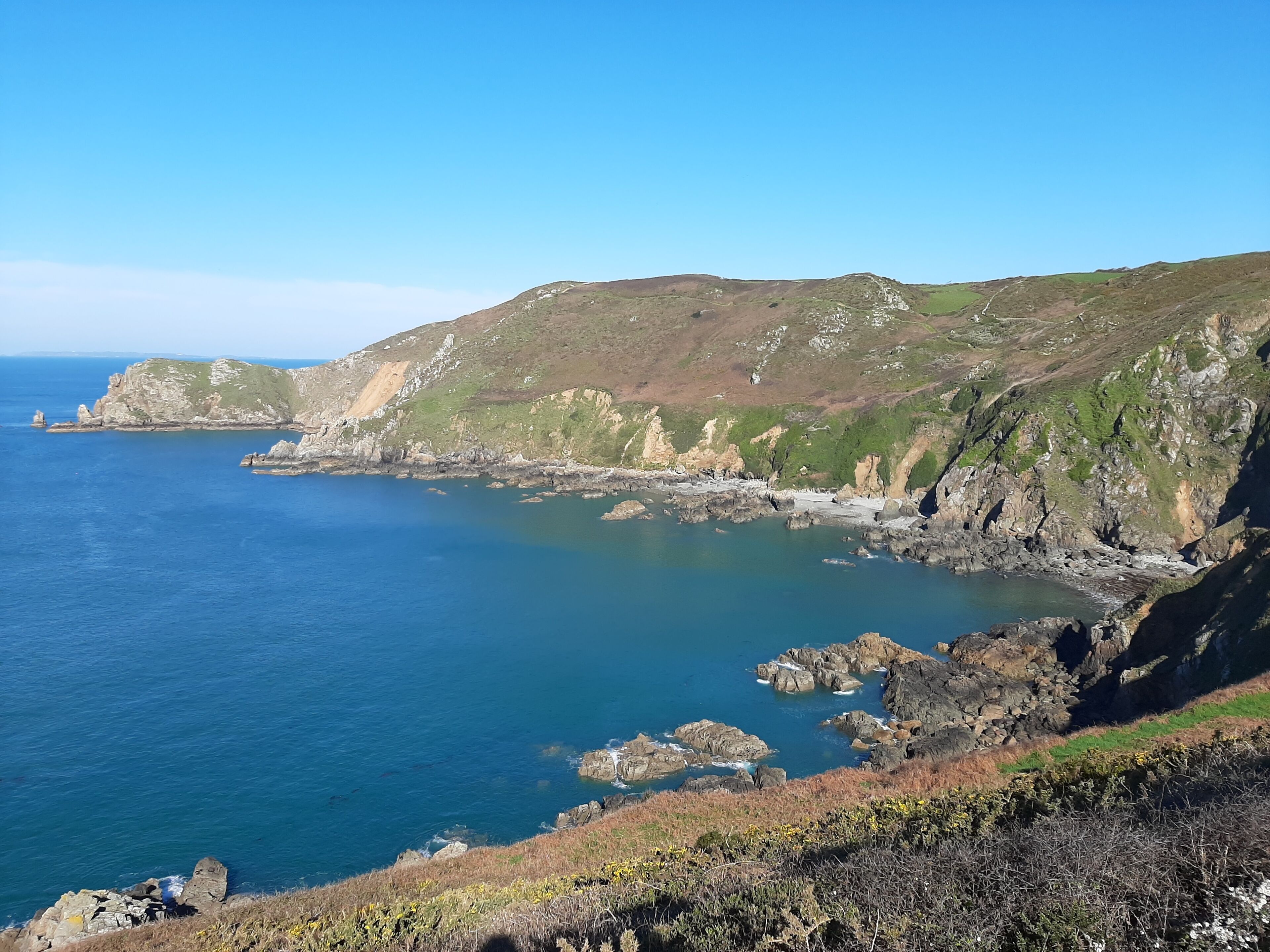 Un paysage côtier caractérisé par des falaises rocheuses et une mer d’un bleu limpide.