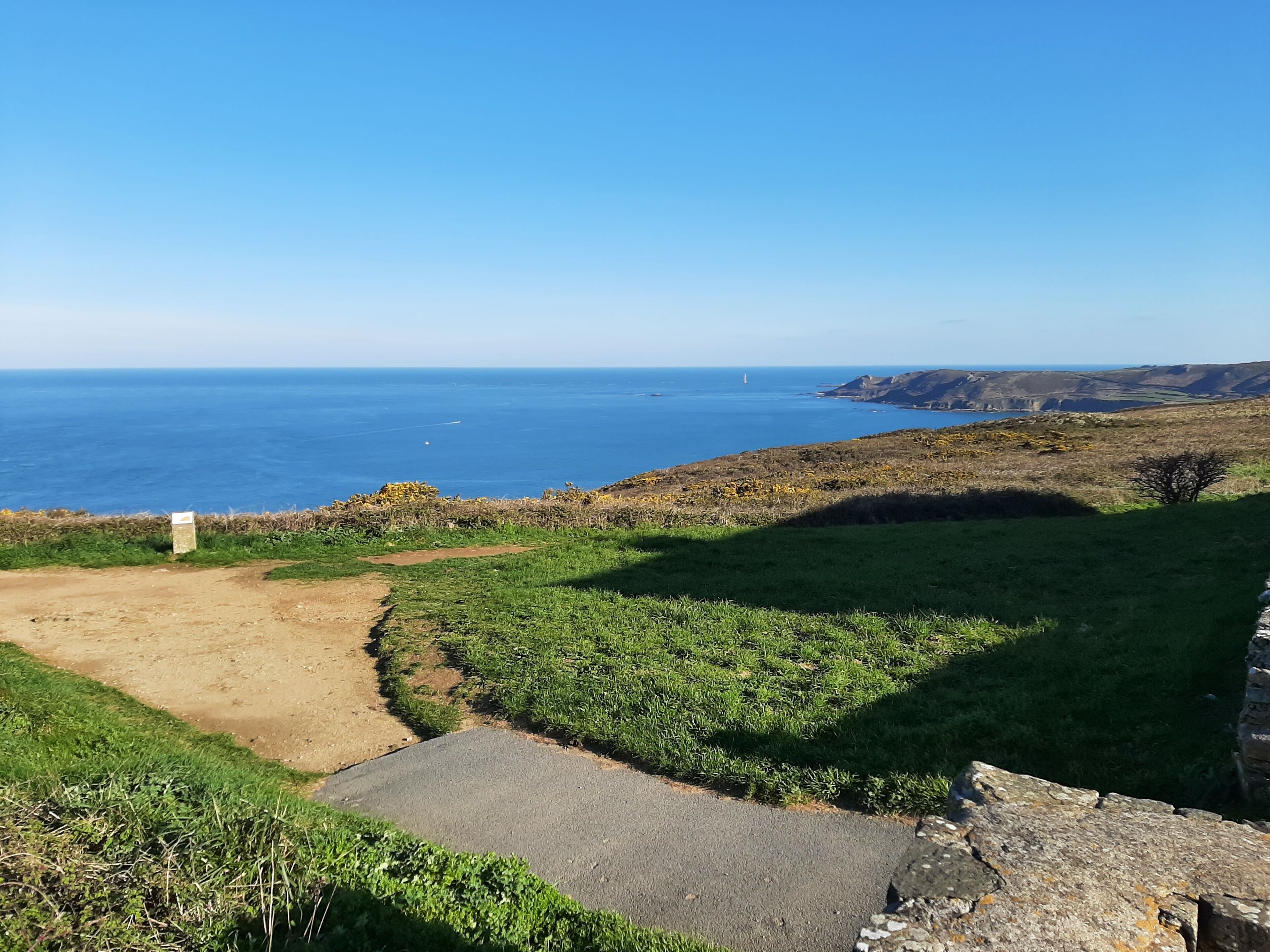 Ett kustlandskap med en grusväg som leder till en gräsyta och en asfalterad del.