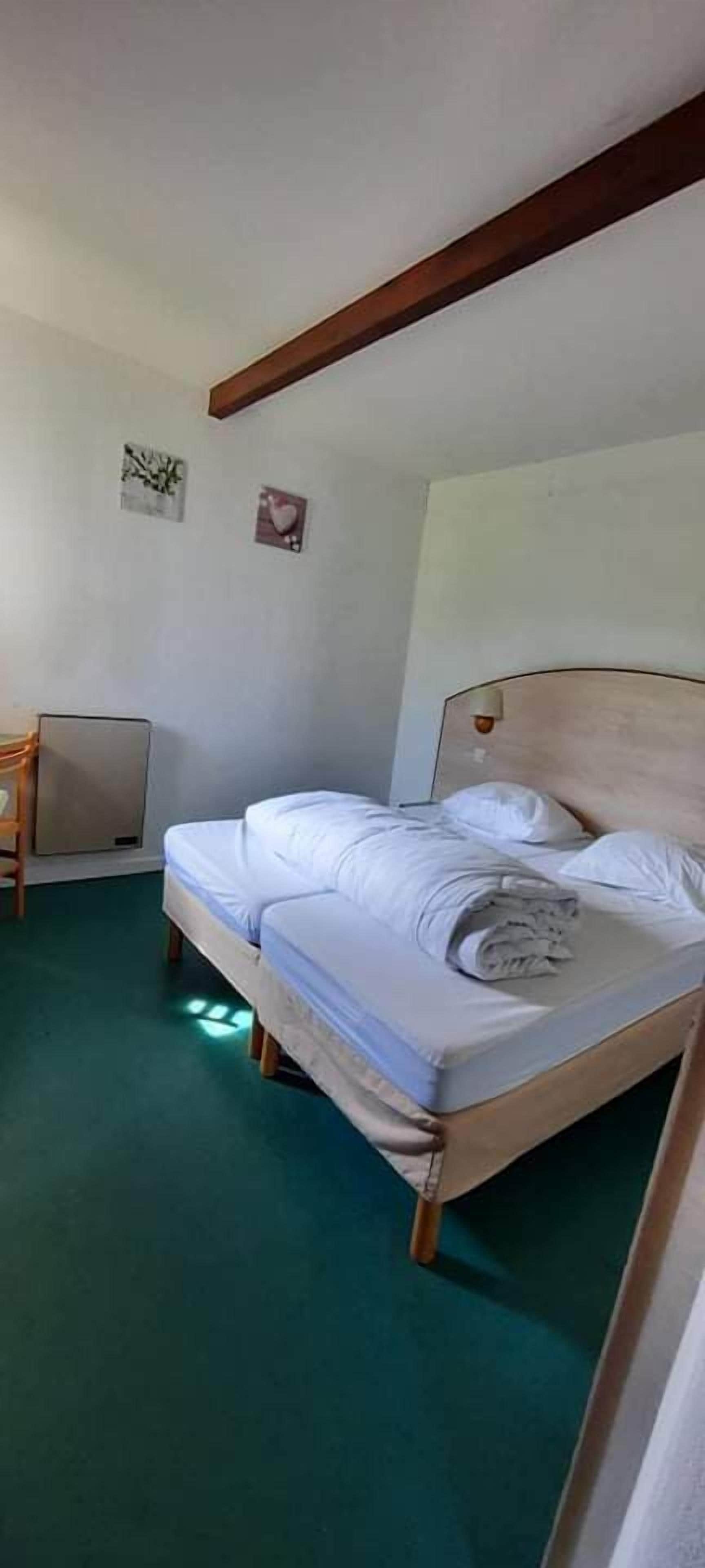 A single bed with a wooden headboard, a small bedside table, and a wall-mounted heater.