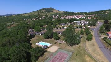 Residents enjoy scenic views of lush greenery and rolling hills from their homes, with access to a tennis court and a winding road connecting to other areas.