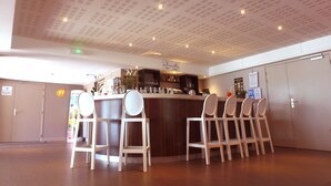 Un espace bar comprenant un comptoir, des tabourets de bar et un plafond orné d’un motif en réseau.
