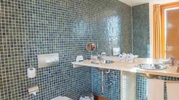 A bathroom with blue mosaic tiles, two sinks, a mirror, and a towel rack.