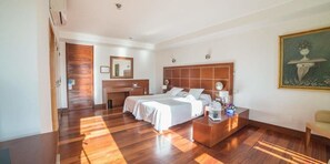 A hotel room with a wooden floor, a bed with white linens, a bedside table with a lamp, and a painting on the wall. - Hotel Acinipo (Ronda)