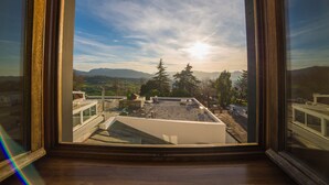 Vista desde una ventana con techo a la vista, cielo despejado y montañas lejanas.