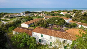 A coastal residential area with white buildings and red-tiled roofs, surrounded by greenery and overlooking the sea. - VVF Île de Ré Sainte-Marie-de-Ré (Sainte-Marie-de-Re)